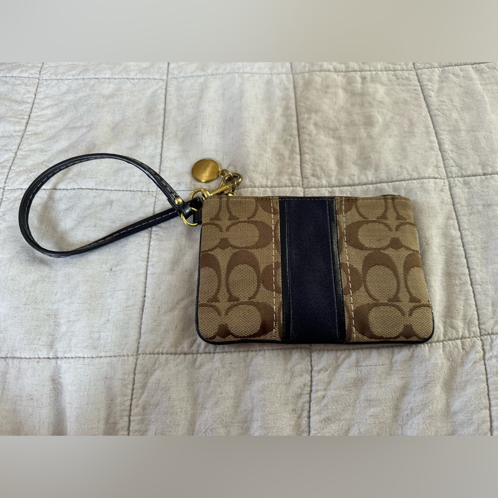 Coach wristlet with navy blue accent stripe and matching leather strap.